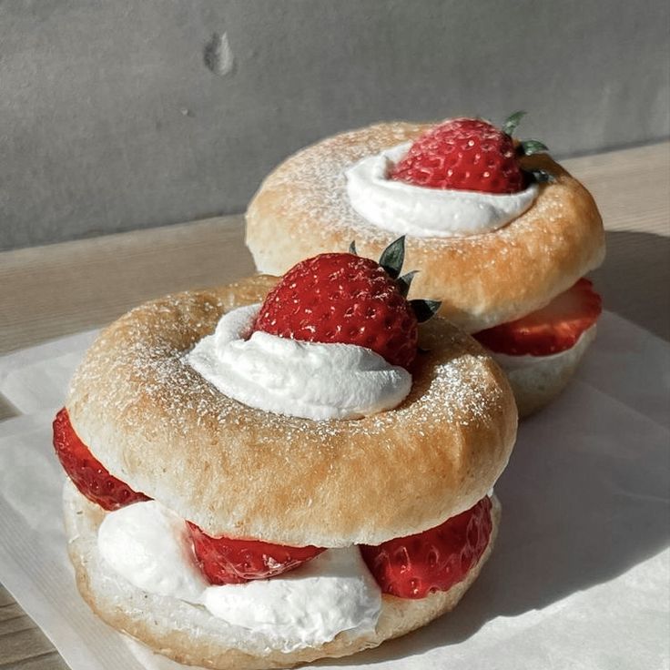 two pastries with strawberries and whipped cream on them