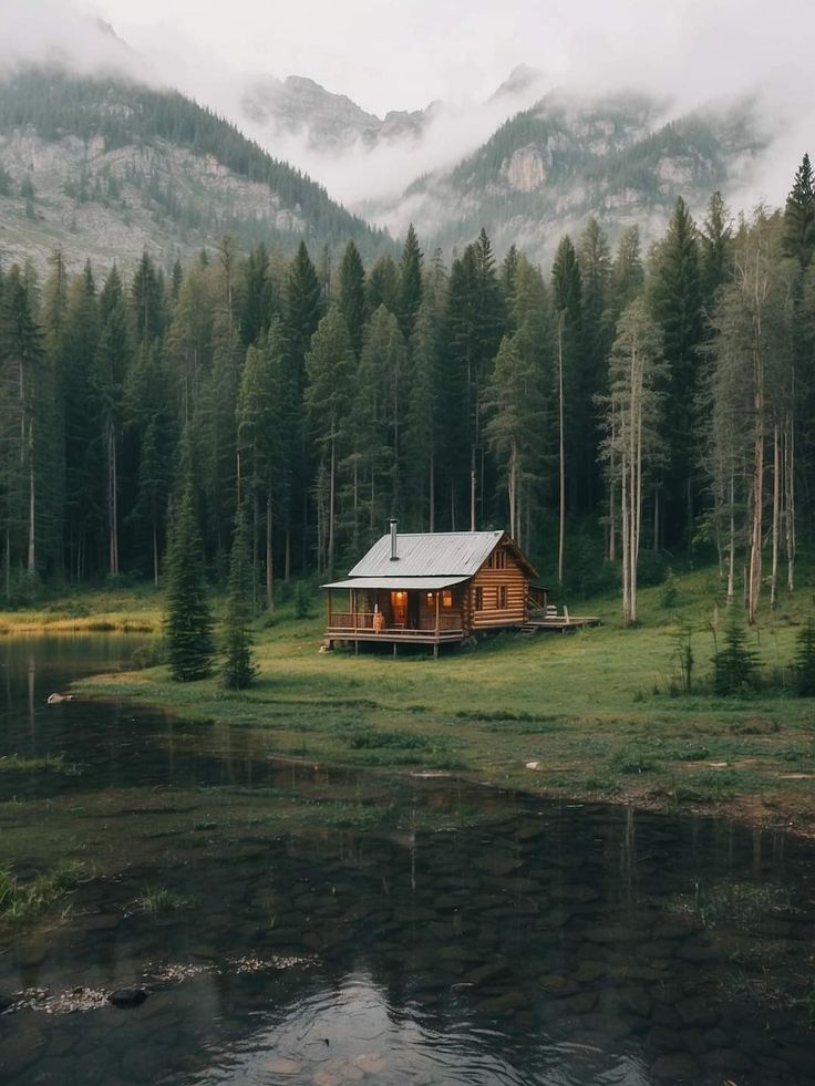 a small cabin in the middle of a forest with mountains in the backgroud