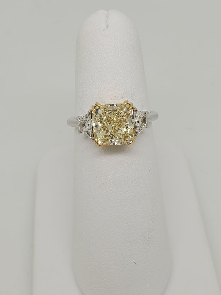 a fancy yellow diamond ring with three diamonds on the band and side stones set in 18k white gold