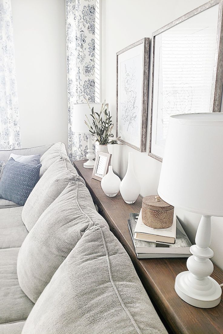 a living room filled with furniture and two framed pictures on top of a wooden table