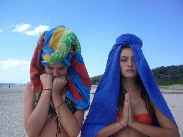 two women in bathing suits on the beach with towels wrapped around their heads and covering their faces