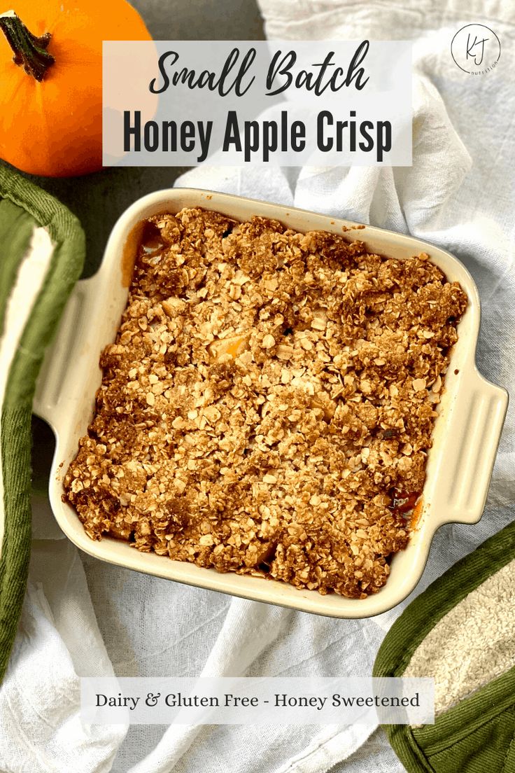 an apple crisp in a white casserole dish next to an orange and green towel