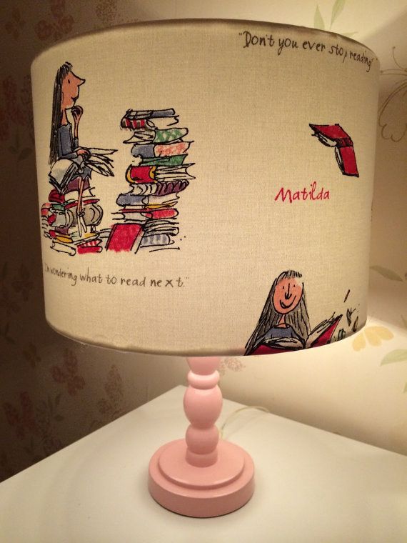 a lamp that has a pink base and a cartoon character on it with words written across the lampshade