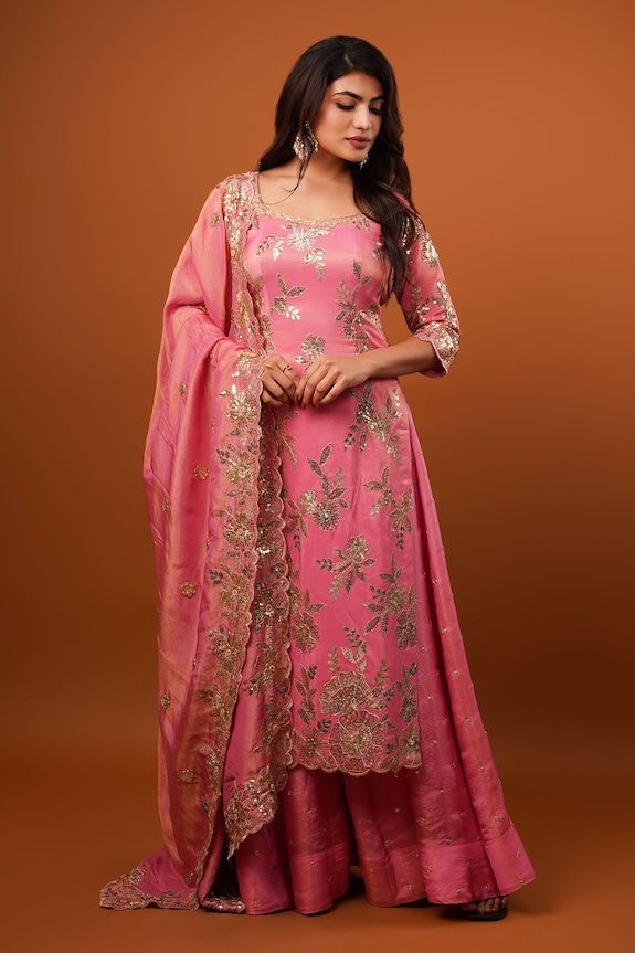 Pink three fourth sleeves kurta with all over Petunia bloom embroidery using gold toned sequin highlights. Paired with an embellished flared sharara and a cutwork sequin bloom border embroidered dupatta. - Aza Fashions Festive Pink Dola Silk Sharara, Diwali Georgette Sharara With Zari Work, Designer Pink Art Silk Sharara, Diwali Zari Work Georgette Sharara, Pink Dola Silk Sharara For Eid, Anarkali Palazzo Set In Banarasi Silk For Wedding, Bollywood Banarasi Silk Palazzo Set For Wedding, Pink Anarkali Sharara In Tissue Silk, Embroidered Art Silk Palazzo Set For Wedding