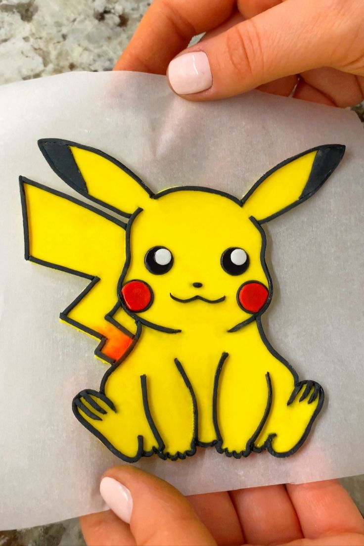 someone holding up a pokemon pin with the pikachu on it's back