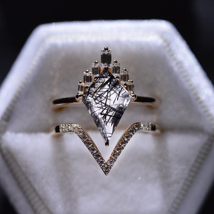 a diamond ring sitting on top of a white cloth covered box with diamonds around it