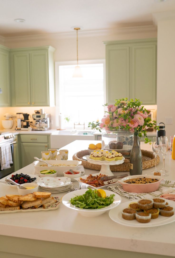 a kitchen filled with lots of food on top of a white counter topped with plates