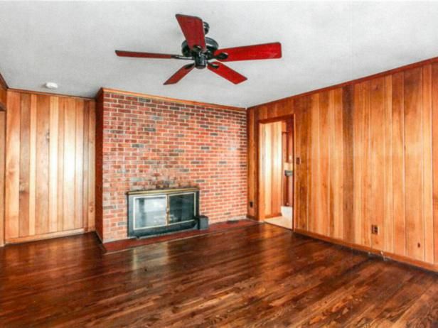 an empty living room with wood paneling and a ceiling fan