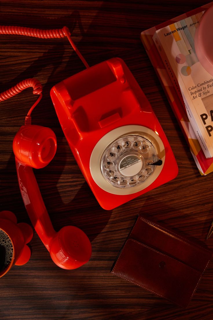 an old red telephone sitting on top of a wooden table