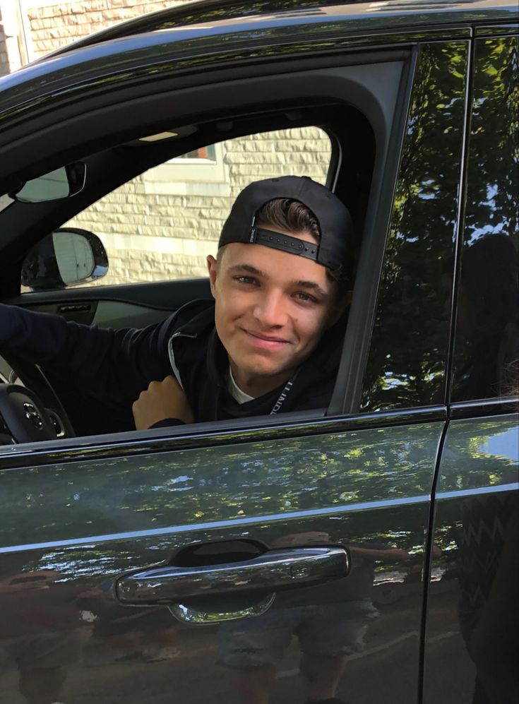 a young man sitting in the driver's seat of a car looking out the window