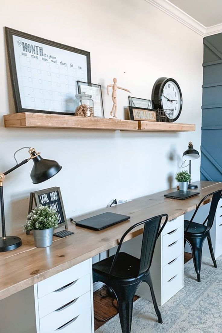 a desk with two chairs and a clock on the wall above it in a home office