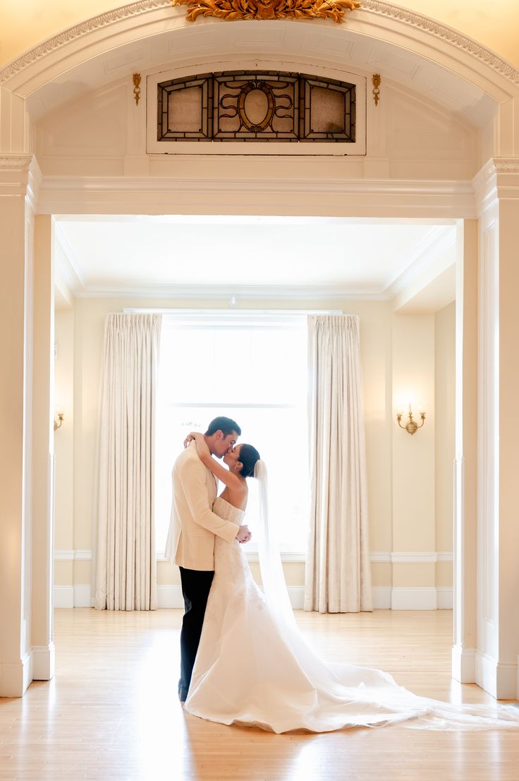 a bride and groom standing in front of a window