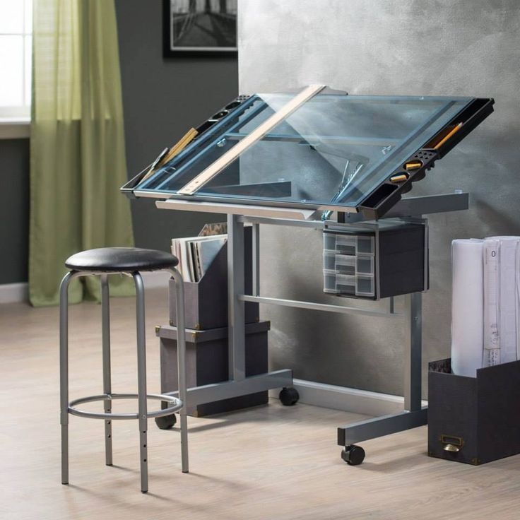 an office desk with a glass top and metal frame on wheels, in front of a gray wall