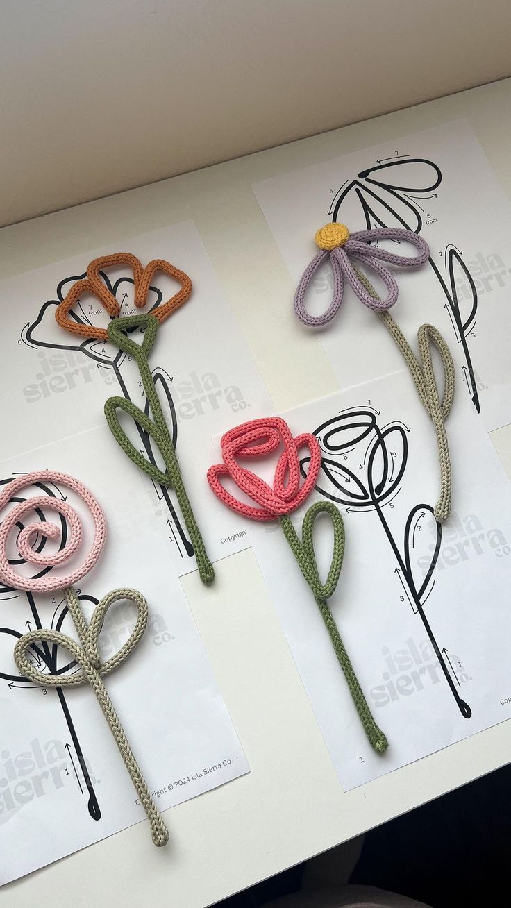 four crocheted flowers sitting on top of a white table next to each other