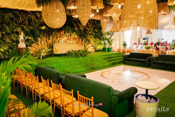 an indoor wedding venue with green couches and hanging chandeliers over the dance floor