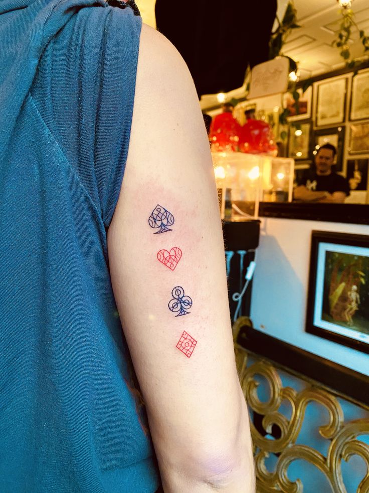 a person with a tattoo on their arm that has four dices in the shape of hearts