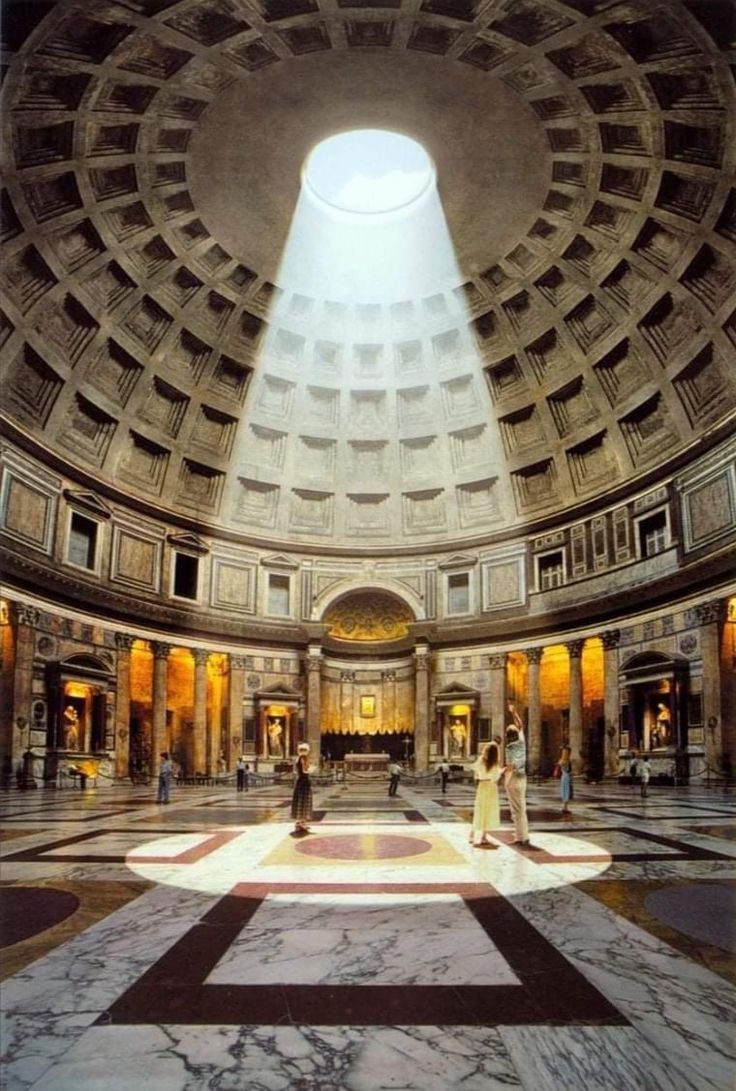 the interior of a large building with people walking around and looking up at the ceiling