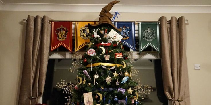 a decorated christmas tree in front of a window with harry potter flags hanging above it