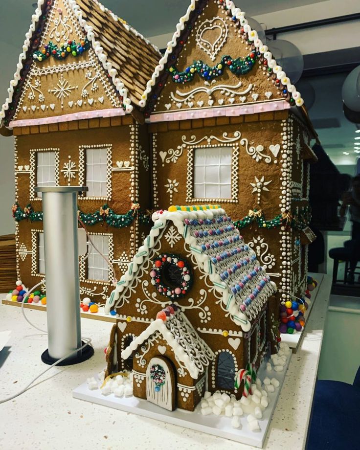 a large gingerbread house is decorated with icing and other holiday decorating items