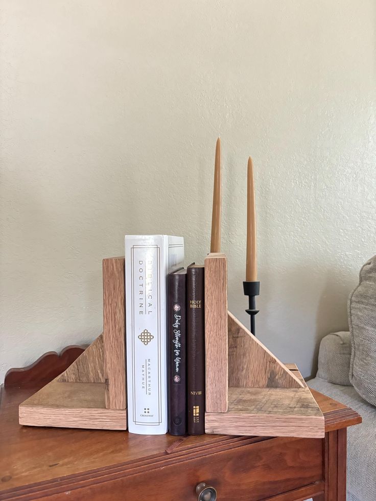 two books are sitting on top of a wooden shelf next to a candle holder and book