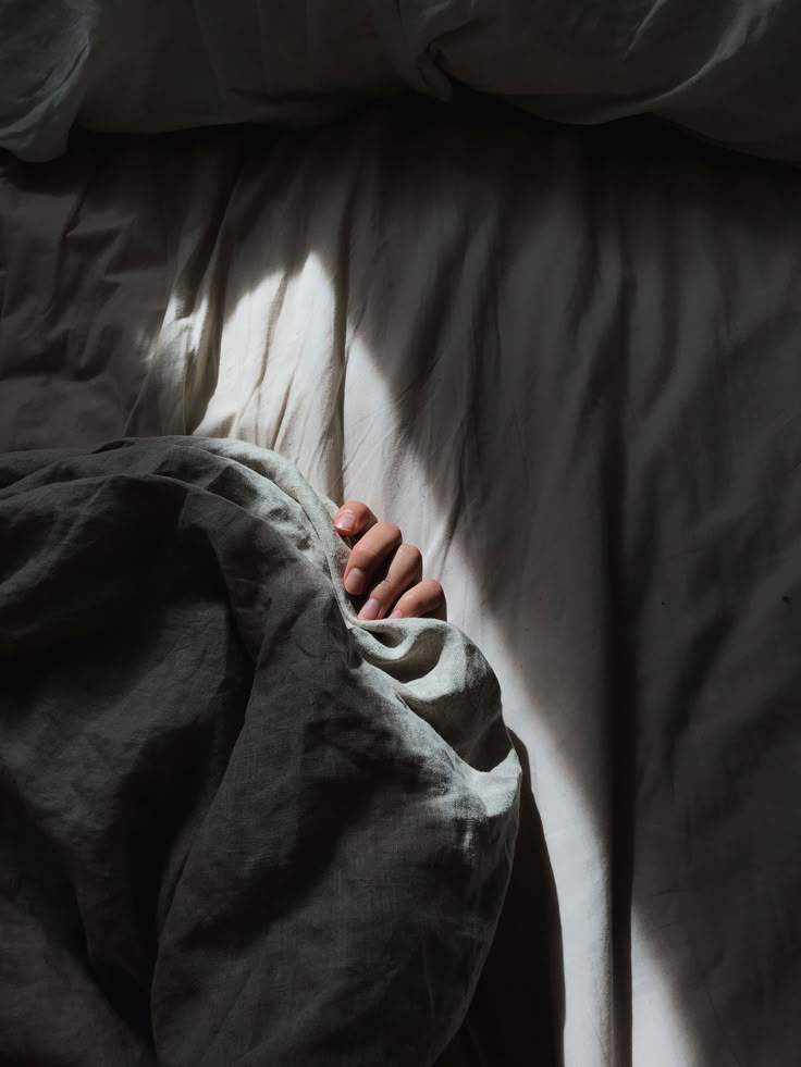 a person's hand under the covers of a bed