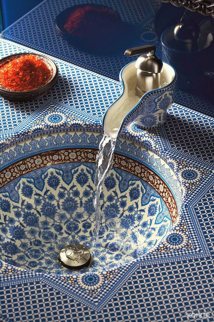 a faucet that is sitting on top of a blue and white bowl with red stuff in it