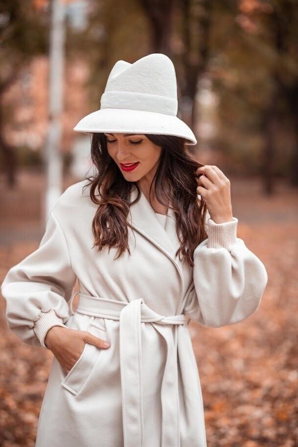 Ivory Millinery Couture Asymmetrical Crown Wide Brim Women  Felt Fedora Hat, Elegant Ledies Velour hat READY to SHIP The hat has long ceased to be just an accessory. Today it plays an essential role in the life of a modern woman. It gives a mood, inspires, complements the image, distinguishes from the crowd, offers exceptional chic elegance and shows the high taste of its owner. The hat is a feminine soul that is so changeable. Today it demonstrates her sole to the whole world, and tomorrow it hides from everyone behind broad brims. Your mood can be emphasized by the geometry and shape of my hats. The combination of brim and crown of the hat is ready to tell a lot about you. Remember this always. And if you don't know which hat is right for you, DM me and get a free consultation on selecti Elegant Fedora Hat For Fall, Beige Wide Brim Fedora For Winter, Elegant Brimmed Felt Hat For Fall, Fitted White Fedora For Spring, Elegant Cream Fedora Hat, Chic White Fedora Felt Hat, White Elegant Fedora, Winter Cream Fitted Fedora, Elegant Cream Wide Brim Fedora