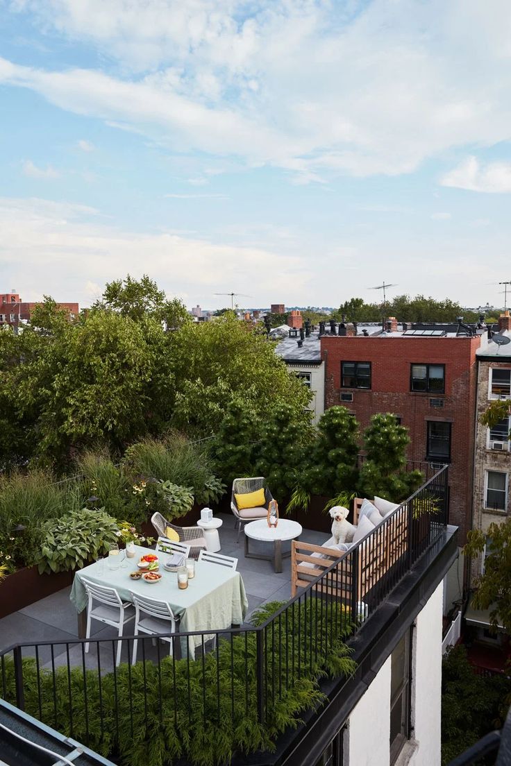 an outdoor patio with tables and chairs on the top floor, surrounded by greenery