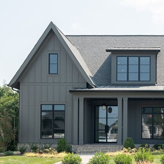 a large gray house with lots of windows on the front and side of it's roof