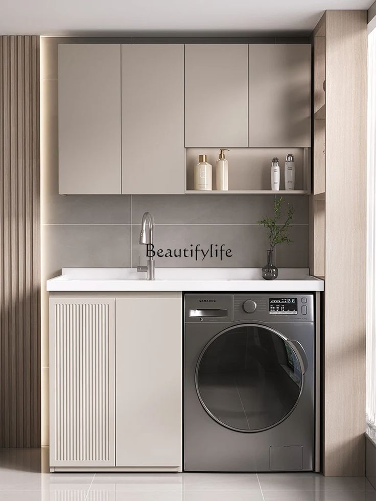 a washer and dryer in a small room with beige cupboards on the wall