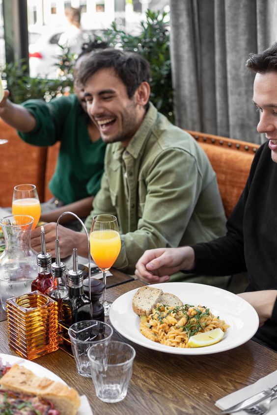 two men sitting at a table with plates of food and drinks in front of them