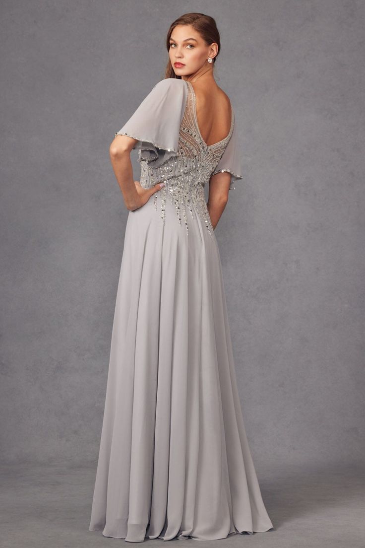 the back of a woman wearing a grey evening gown with sheer shoulders and beading