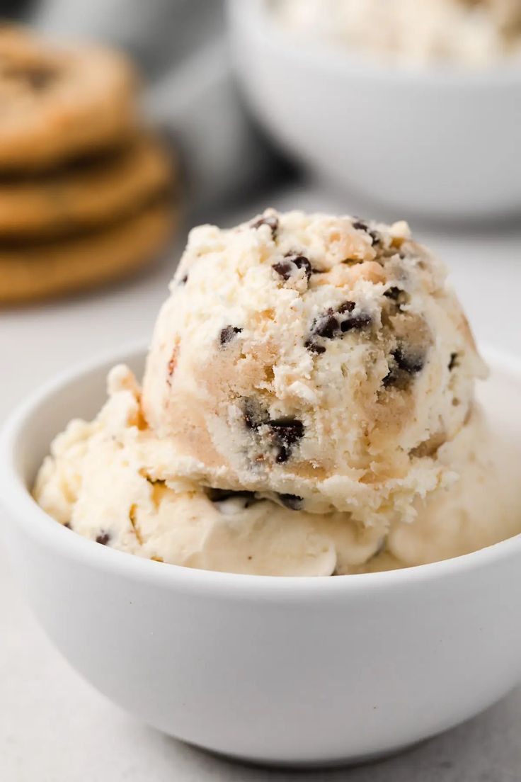 a bowl full of ice cream with cookies in the background