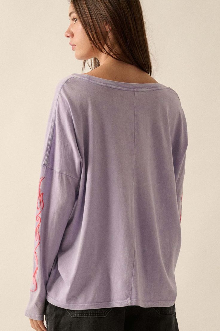 Mineral washed graphic t-shirt. Vintage-style "But She's Hot" text print with flame graphics. Long sleeves with flame print. Dropped shoulder. Round neckline. Center-back seam. Oversized fit. 100% Cotton. Imported top designed and printed in LA. Model wears size S. Purple Soft-washed Relaxed Fit Tops, Oversized Purple Lounge Top, Oversized Purple Loungewear Top, Oversized Purple Top For Loungewear, Soft-washed Cotton Purple Top, Soft-washed Purple Cotton Top, Purple Graphic Print Tops For Loungewear, Acid Wash Washed Tops For Fall, Oversized Acid Wash Cotton Tops