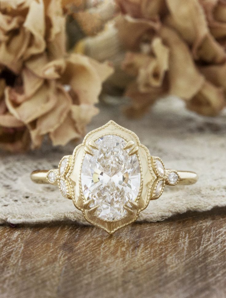 a close up of a ring on a wooden surface with flowers in the back ground