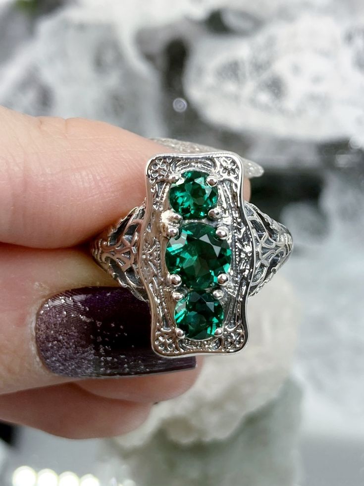 "Natural Green Emerald Ring 3Stone Rectangle Design#60 Custom Made This is a lovely late Victorian era reproduction ring in solid sterling silver. The gorgeous filigree ring is set with 3 round-cut Natural Green Emerald (color/heat treated) gemstones. The 2 smaller gems are 4.5mm in diameter, and the center one is 6mm in diameter. This filigree setting is a casting from an actual Antique ring; notice the amazing etched band... The ring sits 3/4th\" (19mm) NS on the finger. The quality of the sil Elegant Sterling Silver Emerald Three Stone Ring, Rectangular Stone Ring Hallmarked For Anniversary, Hallmarked Rings With Rectangular Stone For Anniversary, Rectangular Stone Hallmarked Rings For Anniversary, Art Deco Rectangular Emerald Ring For Anniversary, Art Deco Jewelry With May Birthstone, Art Deco Rectangular Emerald Anniversary Ring, Art Deco May Birthstone Jewelry, Heirloom Oval Emerald Ring With Three Stones