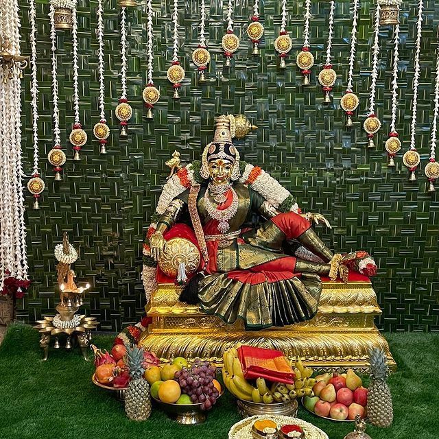 an idol sitting on top of a table filled with fruits and vegetables in front of a green wall