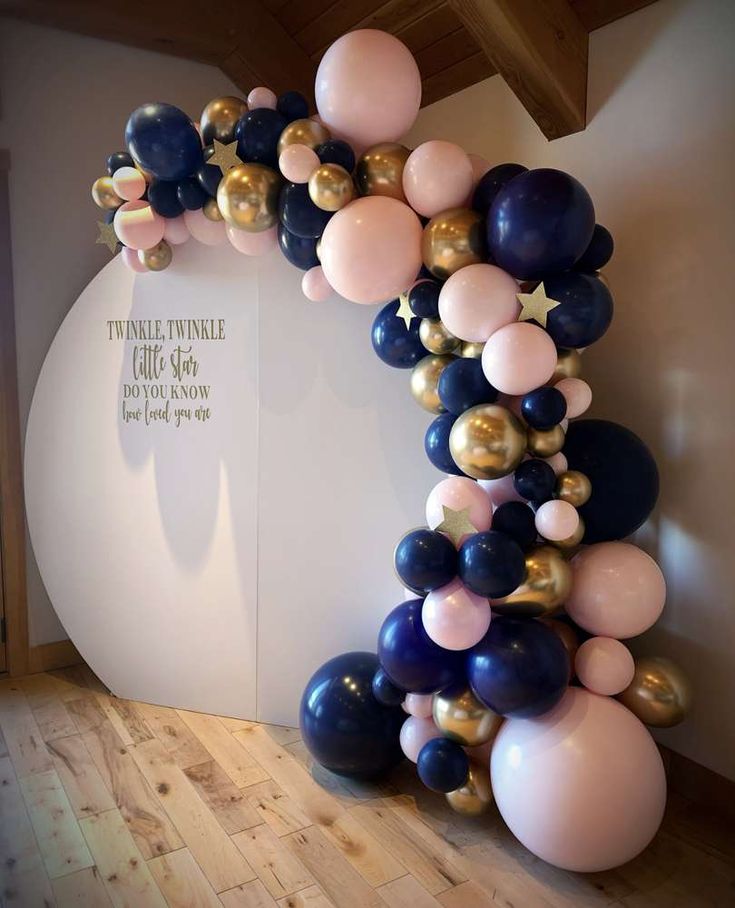 a balloon arch in the shape of a star is decorated with blue, pink and gold balloons