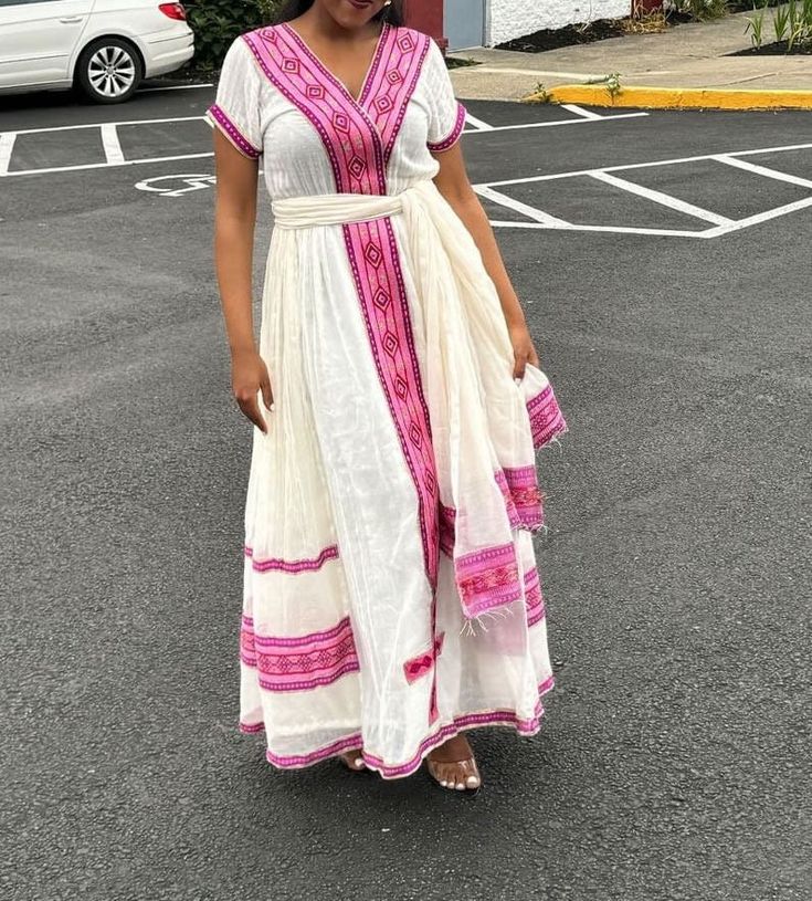 Simple Ethiopian dress with a beautiful trim and  embroidery. This dress comes with full netela (two panel 2m scarf). Model is wearing a M but It can be custome made in any size. please send your size with your order and your phone number. phone numbers are required on the shipping form. Pink Maxi Dress For Traditional Ceremonies, White Short Sleeve Dress For Traditional Ceremonies, Pink Embroidered Dress For Traditional Ceremonies, Fitted Wedding Dress With Embroidered Border, Traditional White Summer Gown, White Maxi Dress For Traditional Ceremonies, White Dresses For Summer Traditional Ceremonies, Elegant Fitted Dress With Embroidered Border, Bohemian Floor-length Dress With Embroidered Border