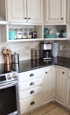 a kitchen with white cabinets and black counter tops