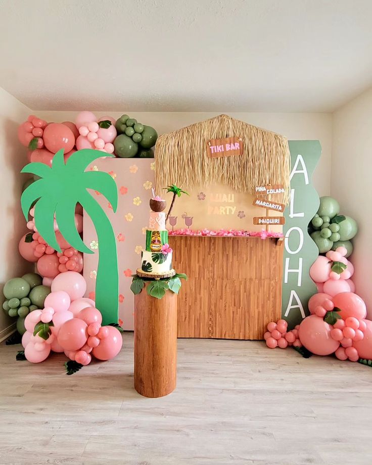 a party setup with balloons, palm tree and tiki hut on the wall behind it