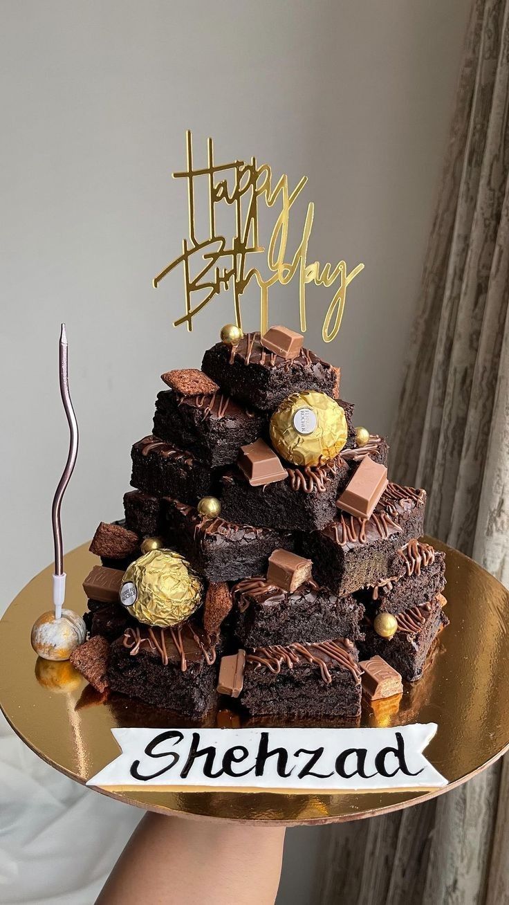 a cake that is sitting on top of a gold platter with chocolates and candies