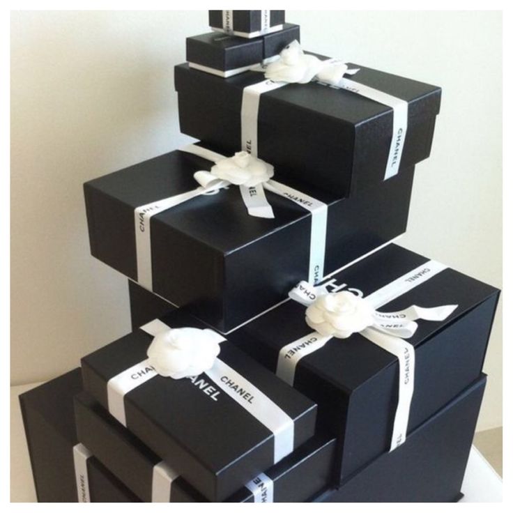 three black boxes with white ribbons are stacked on top of each other and one has a bow