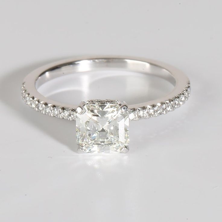 an engagement ring with a cushion cut diamond and pave set diamonds around the band