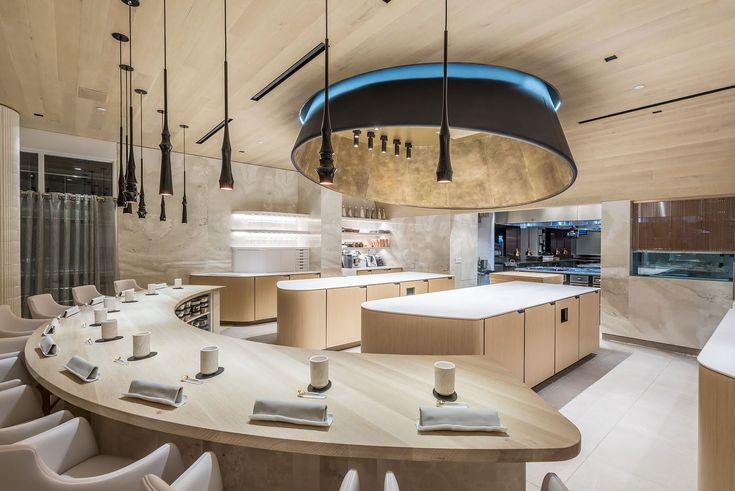 a modern kitchen with an island and dining table in the center, surrounded by white chairs