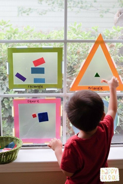 a young boy standing in front of a window looking out at some paper cutouts