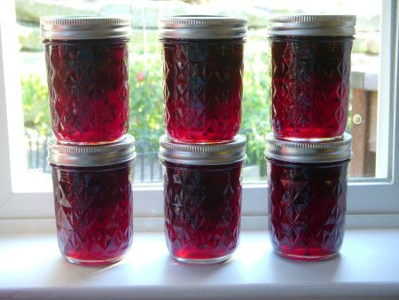 four jars are lined up on a window sill