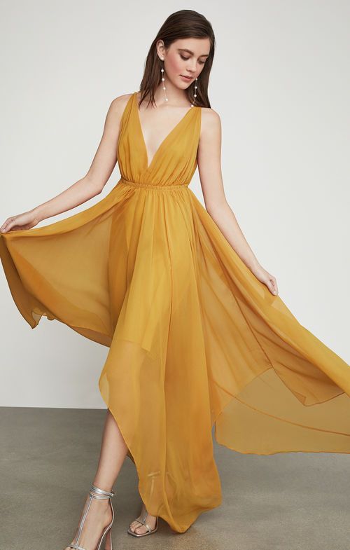 a woman in a yellow dress is posing for the camera