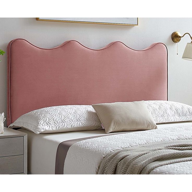 a pink headboard with scalloped edges on a white bed in a bedroom