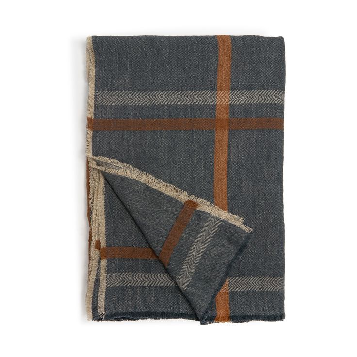 a blue and brown checkered blanket folded on top of a white surface with an orange stripe